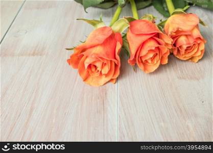 A bouquet of orange roses on wooden table. Copy space