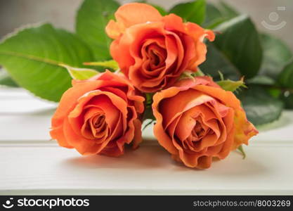 A bouquet of orange roses on wooden table. Copy space