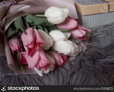 A bouquet of pink and white tulips and a gift box