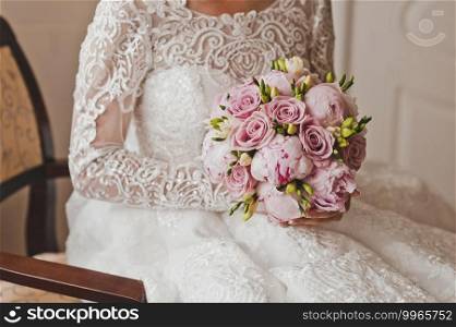 A bouquet of roses and peonies in pink tones in the hands of the bride.. The bride holds a bright wedding bouquet of peonies and roses in her hands 2665.