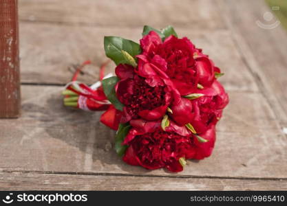 A bouquet of ruby flowers on the floor.. Huge red peonies on the plank floor 2866.