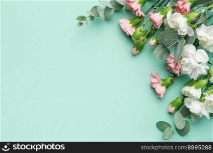 A bouquet of white and pink carnations with eucalyptus branches on a soft green background. Festive background.