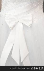 a bow over a bride&rsquo;s white dress, closeup