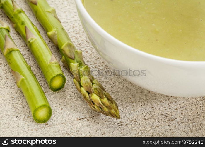 a bowl of asparagus cream soup with green asparagus spears