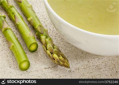 a bowl of asparagus cream soup with green asparagus spears
