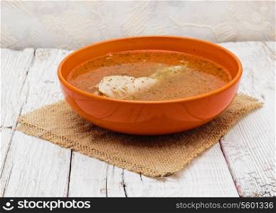 a bowl of chicken soup on a white wooden table