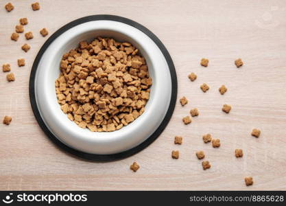 A bowl of dog food on a wooden floor. Dry food in granules.