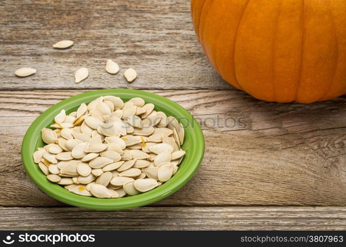 a bowl of fresh pumpkin seeds on weathered wood