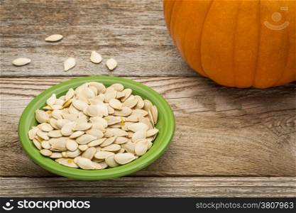 a bowl of fresh pumpkin seeds on weathered wood