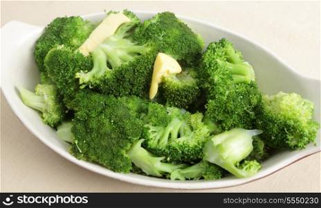 A bowl of lightly boiled fresh broccoli topped with melting butter