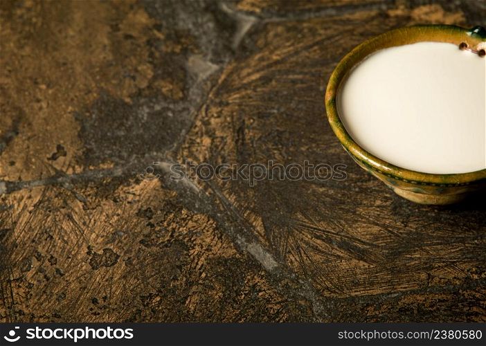 a bowl of milk on an old antique tile. oriental spices on an old paving stone