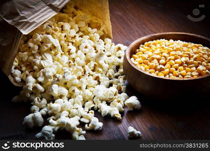 A bowl of popcorn and kernels on a wooden table