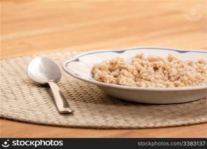A bowl of porridge on a table with a spoon;