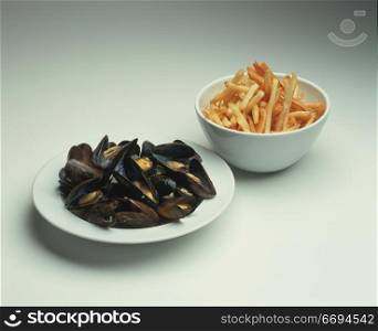 a bowl of seafood and a bowl of chips/fries