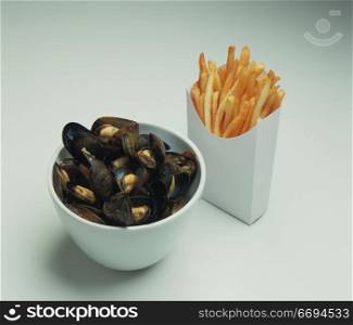 a bowl of seafood and a carton of chips/fries