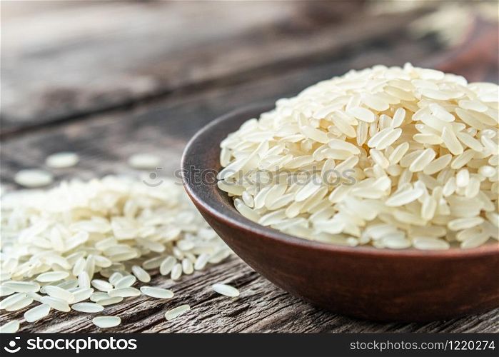 A bowl of white rice against the background of old boards near sprinkled rice. Jasmine rice for cooking. Close-up.. A bowl of white rice against the background of old boards near sprinkled rice. Jasmine rice for cooking.