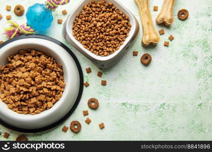 A bowl with dog food, dog treats and toys on a wooden floor. Concept of healthy food for dogs.