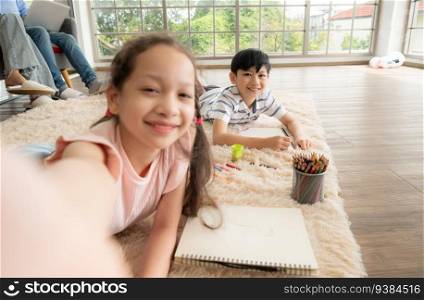 A boy and a daughter from an asian family. The children are having fun in the art of drawing and selfie of themselves on social media.