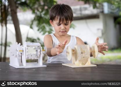 A boy and pay attention to learning the simulation mechanism robot model wooden on table at home.