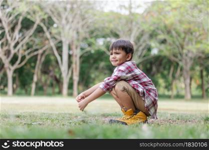 A boy childs arms raised with enjoy on the lawn and wearing hiking shose is over size.Child having fun in summer.