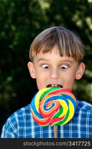 a boy going cross eyed as he looks down at the lollipop that is too big. cross eyed boy eating lollipop