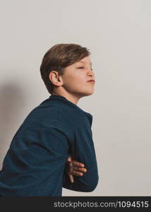 a boy in a dark blue jersey making grimace, against a white wall