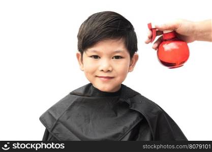 A boy is sprayed his hair by hair dresser isolated over white background