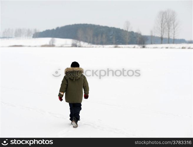 A boy on a winter evening on the frozen lake
