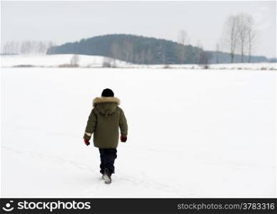 A boy on a winter evening on the frozen lake