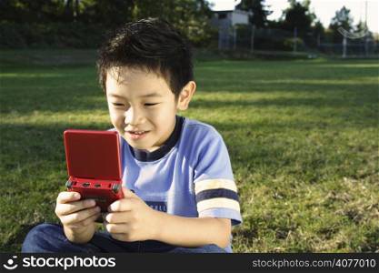 A boy playing video game at a park
