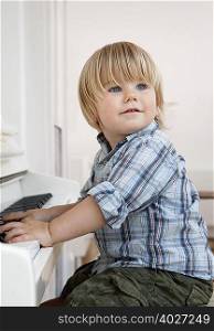 A boy toddler sitting at a piano
