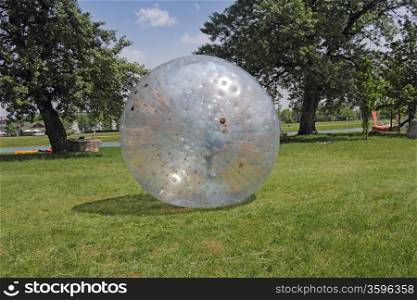 A boy walks in a large plastic balls on the green grass