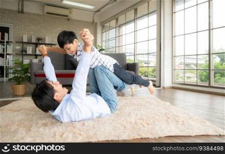 A boy wants to fly with his father by using his legs to help him fly high off the ground. in the living room