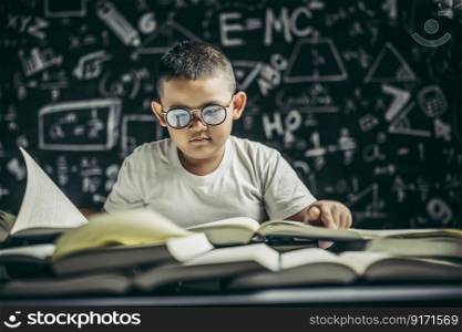 A boy with glasses sitting in the classroom reading