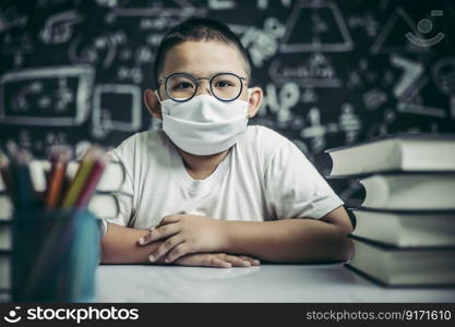 A boy with glasses sitting in the classroom studying