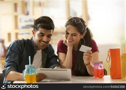 A boy with laptop and a girl with card shopping online. 