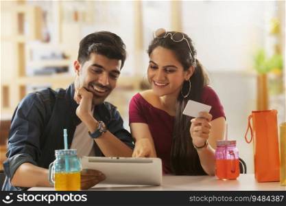 A boy with laptop and a girl with card shopping online. 