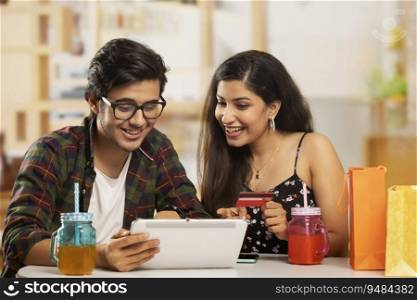 A boy with laptop and a girl with credit- card shopping online. 