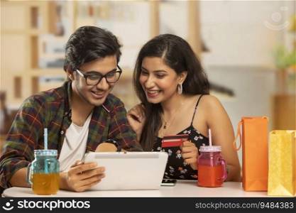 A boy with laptop and a girl with credit- card shopping online. 