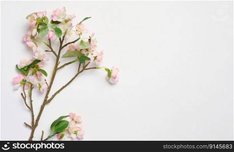 A branch with textile cherry blossoms on a white background, top view, home decor. Copy space