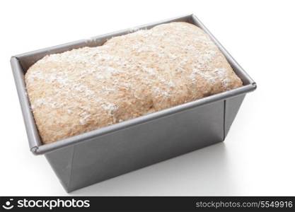 A bread tin with wholemeal dough on its final rise and about to go into the oven