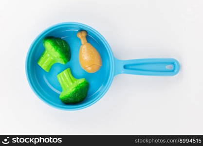 a breakfast with broccoli in a pan on a white background, children’s plastic toy. breakfast with broccoli in a pan on a white background, children’s plastic toy