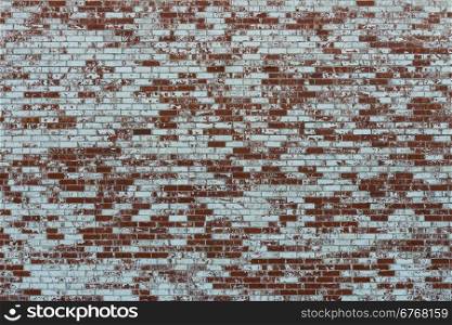 A brick wall, partially covered in white paint