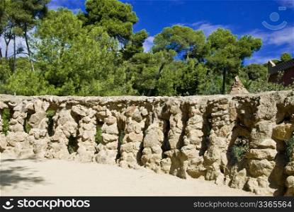 a bricked stone railing styled by antonio gaudi in park guell and a wonderful blue sky