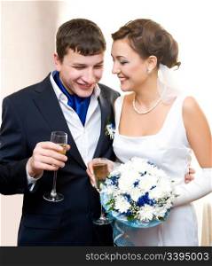 a bridegroom and his bride hold glasses of champagne and smile
