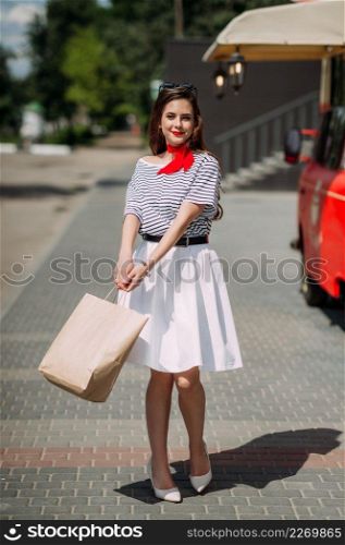 A bright girl walks through the summer streets of Arzamas.. Portrait of an airy beauty on a summer walk by a red car 4195.