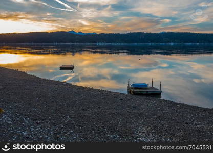 A brilliant sunset is reflected in the waters of Hood Canal in Washington State. The Olympic Mountains can be seen in the distance.