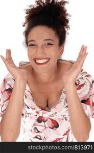 A broadly smiling multi-racial woman standing in close up with her hands on her face in a nice summer dress and curly black hair in abun on her head, isolated for white background