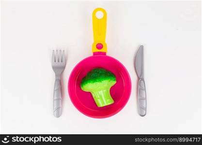 a broccoli cabbage in a pan with a spoon and fork on a white background. broccoli cabbage in a pan with a spoon and fork on a white background