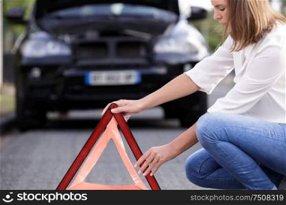 a broken car a triangle sign a woman